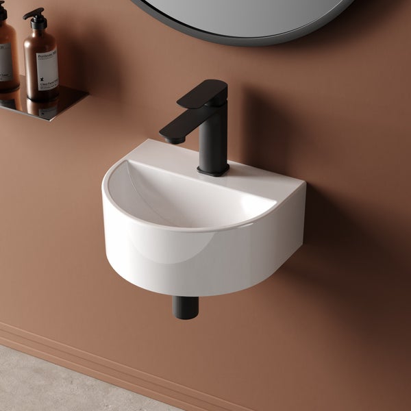 Halbrundes Waschbecken mit schwarzem Wasserhahn an einer Wand montiert