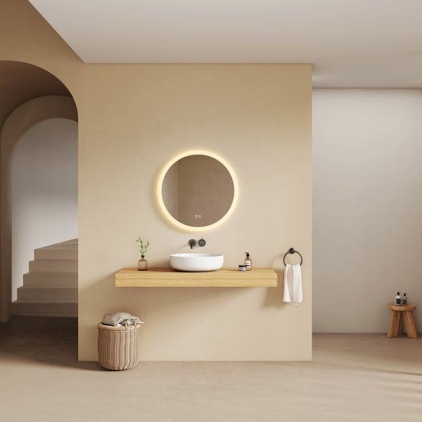 Modernes Badezimmer mit beleuchtetem runden LED-Spiegel, weißem Aufsatzwaschbecken auf einer Holzkonsole und schwarzen Armaturen.