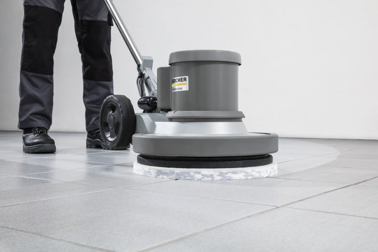 Eine Person benutzt eine Karcher Professional Einscheibenmaschine zum Reinigen eines Fliesenbodens.
