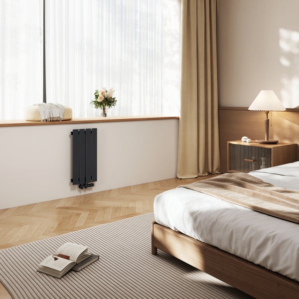 Moderner Designheizkörper unter einem Fenster in einem gemütlichen, in warmen Tönen gehaltenen Schlafzimmer mit Holzmöbeln und Parkettboden.