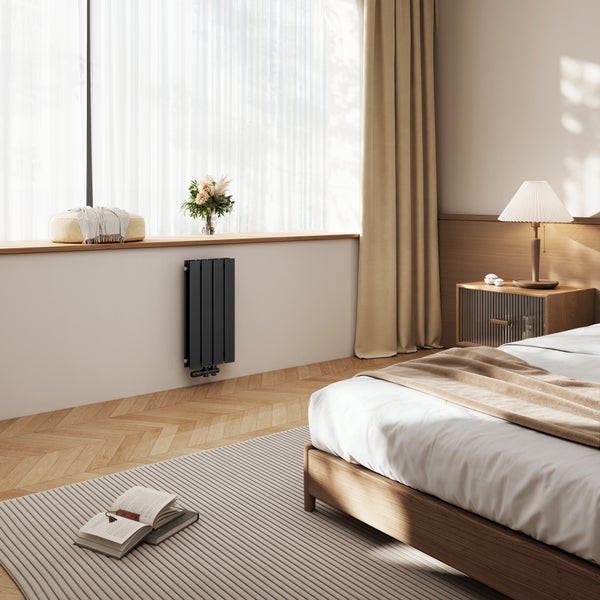 Moderner schwarzer Designheizkörper an einer hellen Wand im Schlafzimmer mit Holzmöbeln und Fischgrätparkett.