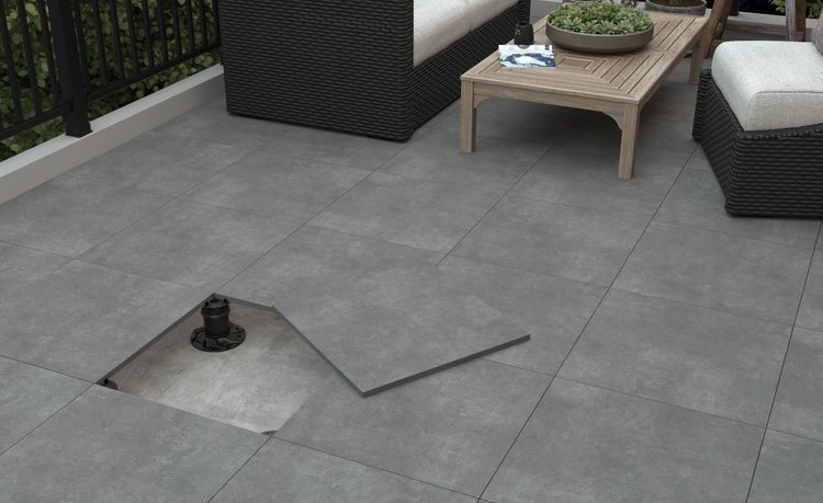 Terrassenplatten auf Stelzlagern verlegt auf einem Balkon mit Loungemöbeln und Holztisch.