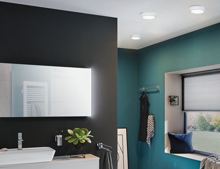 Helles Badezimmer mit Waschtisch, Spiegel, Deckenleuchten und Fenster