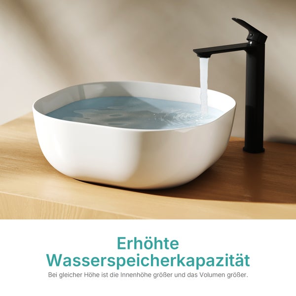 Weißes Aufsatzwaschbecken auf einer Holzplatte mit schwarzer Armatur und fließendem Wasser.