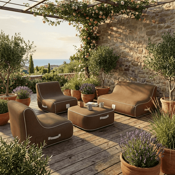 Mediterrane Terrasse mit braunen Outdoor-Lounge-Möbeln, Steinmauer, Holzdeck und Blick auf das Meer.