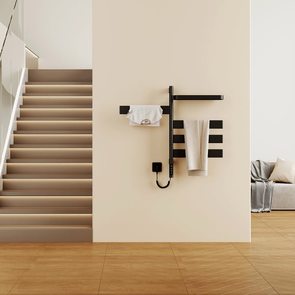 Moderner elektrischer Handtuchheizkörper in Schwarz an einer beigen Wand in einem hellen Raum mit beleuchteter Treppe und Holzfußboden.