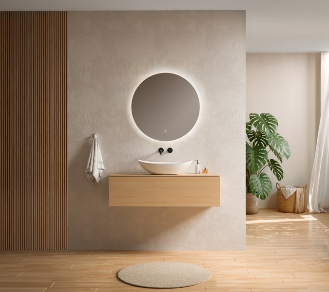 Modernes Badezimmer mit beleuchtetem Rundspiegel, weißem Aufsatzwaschbecken auf einem schwebenden Holzunterschrank und schwarzen Wandarmaturen.