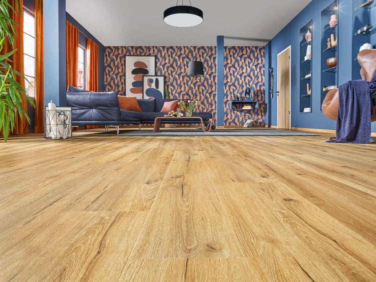 Geräumiges Wohnzimmer mit Laminatboden in Eichenoptik, blauem Ledersofa, gemusterter Tapete und moderner, heller Inneneinrichtung.