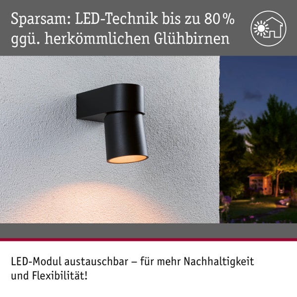 Schwarze LED-Wandleuchte an einer Wand mit Garten im Hintergrund.
