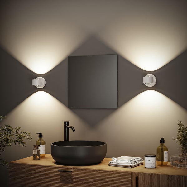 Badezimmer mit Waschbecken, Spiegel und Wandleuchten für eine helle und moderne Atmosphäre