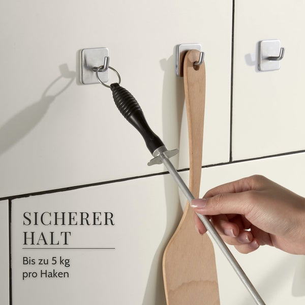 Drei quadratische Klebehaken an einer Wandfliese mit Küchenutensilien, Tragkraft bis zu 5 Kilogramm pro Haken.