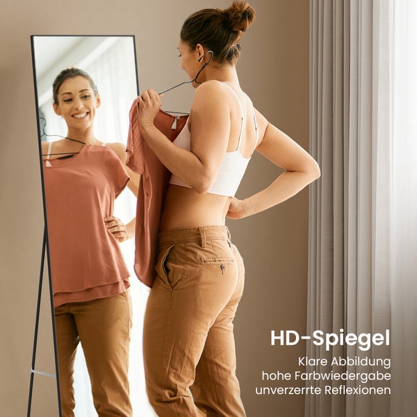 Frau probiert Kleidung vor einem Ganzkörperspiegel mit schlankem Rahmen an