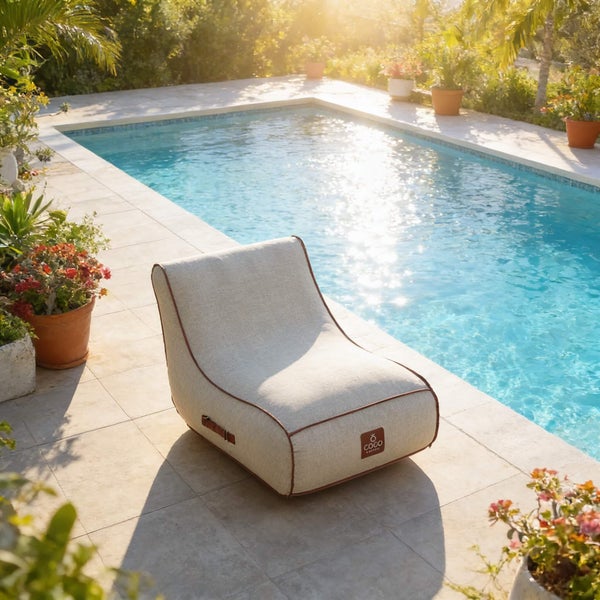 Outdoor-Sitzsack-Sessel mit Coco Logo aus strukturiertem Stoff am Pool auf einer gefliesten Terrasse mit Pflanzen.