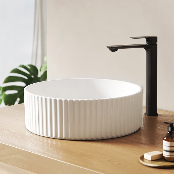 Keramikwaschbecken mit Rillen und schwarzer Armatur auf Holztisch
