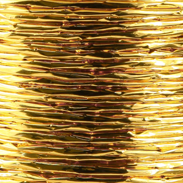 Strukturierte goldfarbene Metallfolie mit horizontaler Riffelung und glänzender Oberfläche.