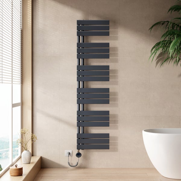 Moderner elektrischer Badheizkörper in Anthrazit an einer hellen Fliesenwand in einem hellen Badezimmer neben einer weissen Badewanne.