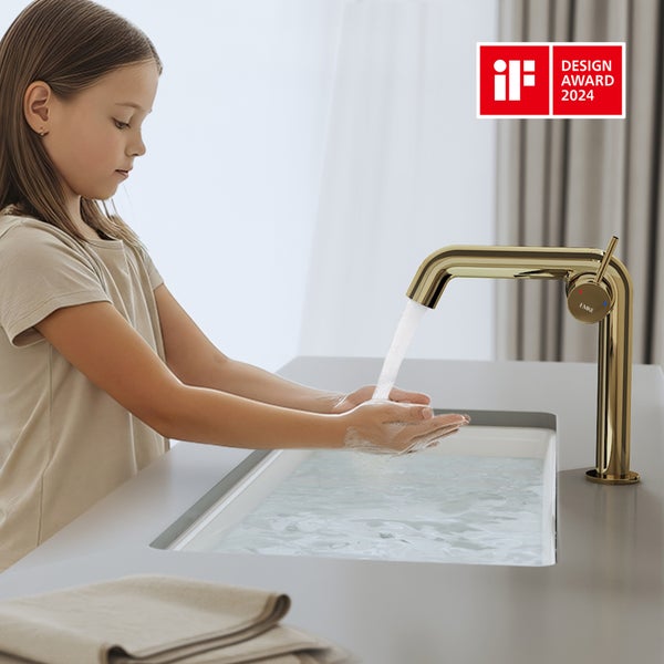 Mädchen wäscht sich die Hände unter einem goldenen Wasserhahn im Badezimmer mit dem Design Award 2024 Siegel.