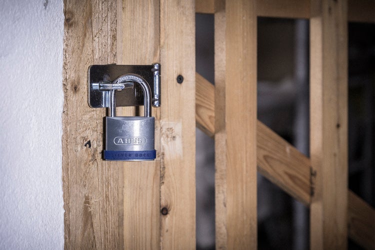 ABUS Silver Rock Vorhängeschloss an einer Metallüberfalle an einer Kellertür aus Holz.