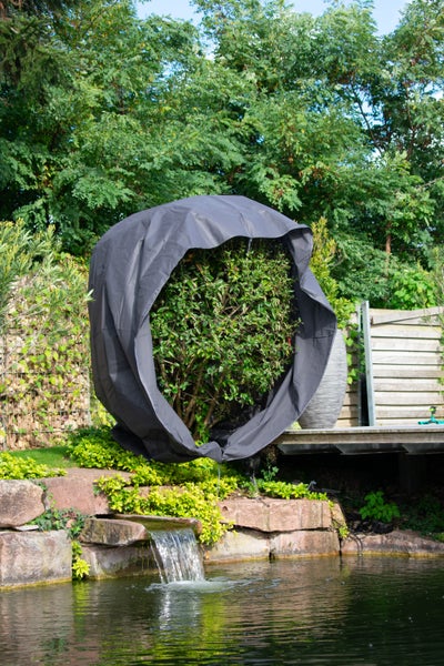 Eine wetterfeste Schutzhaube für Pflanzen oder Sträucher in einem Garten am Teichufer.