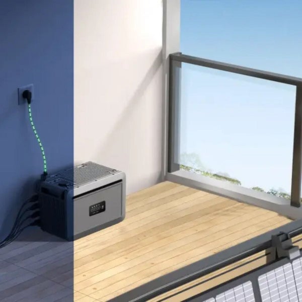 Tragbarer Stromspeicher auf einem Balkon mit Holzbelag, angeschlossen an eine Steckdose und ein Solarmodul.