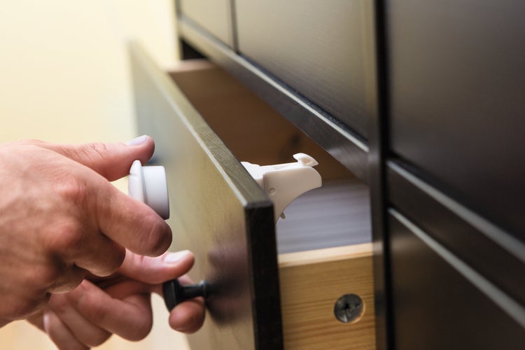 Magnetisches Kindersicherungsschloss für Schubladen wird mit einem Magnetschlüssel an einer Kommode geöffnet.