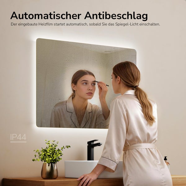 Beleuchteter Badezimmerspiegel mit Antibeschlag-Funktion und Spritzwasserschutz, Frau am Waschbecken mit Armatur in hellem Badezimmer.