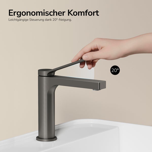 Einhand-Waschtischmischer in Anthrazit auf weißem Waschbecken, Hand bedient den um 20 Grad geneigten Hebel für ergonomischen Komfort.
