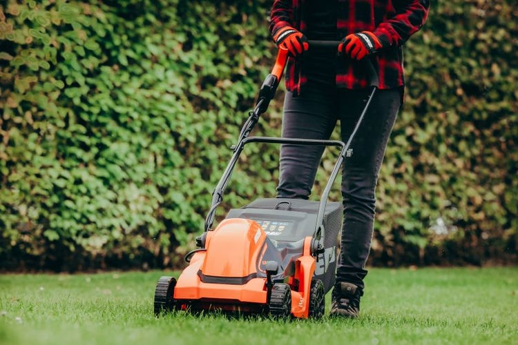Person benutzt einen Rasenmäher auf einer Rasenfläche.