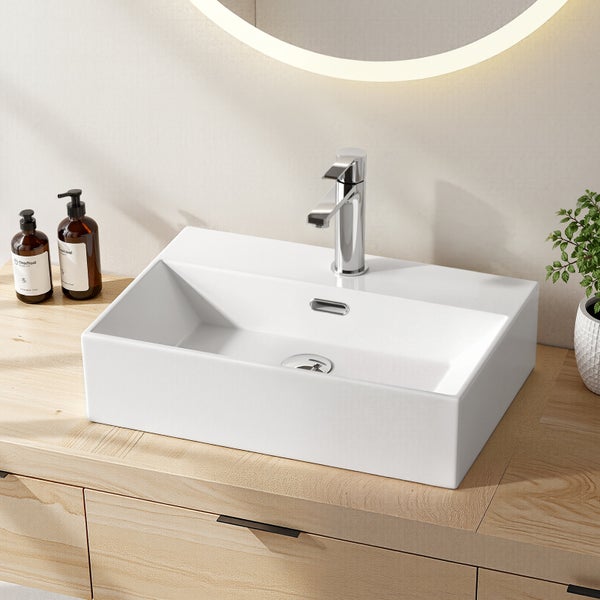 Modernes helles Badezimmer mit weißem rechteckigem Keramik-Aufsatzwaschbecken, verchromter Armatur, Holzunterschrank und beleuchtetem Spiegel.
