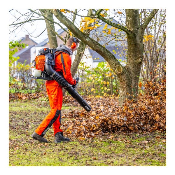 Mann mit Rückentrage-Laubbläser bei der Arbeit im Garten