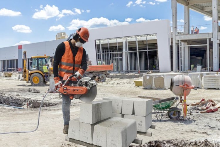 Bauarbeiter schneidet Porenbetonstein mit Steinsäge auf einer Baustelle.