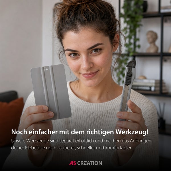 Eine Frau hält eine Rakel und ein Cuttermesser für das Anbringen von Klebefolie. AS Creation Logo.