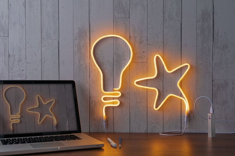 Dekorative LED-Leuchten in Form einer Glühbirne und eines Sterns auf einem Tisch mit Laptop