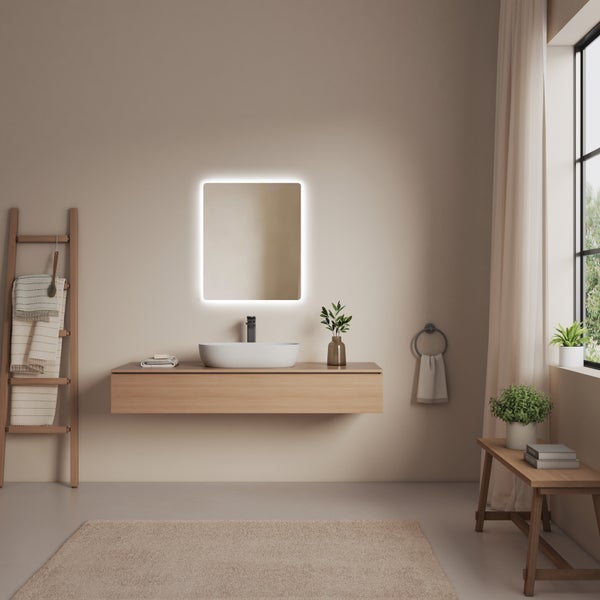 Helles Badezimmer mit Waschtisch, beleuchtetem Spiegel, Handtuchleiter und Teppich für eine freundliche Atmosphäre.