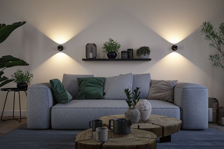 Wohnzimmer mit grauer Couch, Wandregal und Wandleuchten für Wohnraumbeleuchtung