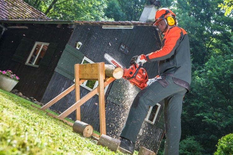 Eine Person sägt mit einer Echo Kettensäge Holz auf einem Sägebock im Freien.