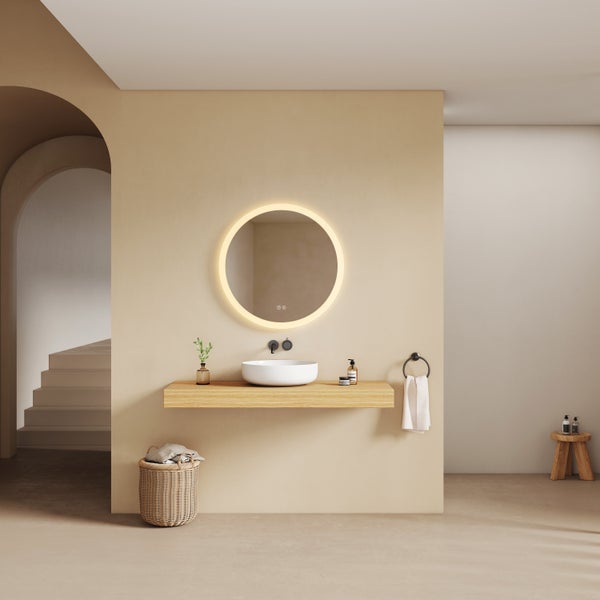 Rund beleuchteter Badspiegel über weißem Aufsatzwaschbecken auf einer Holzkonsole in einem modernen, minimalistischen Badezimmer.