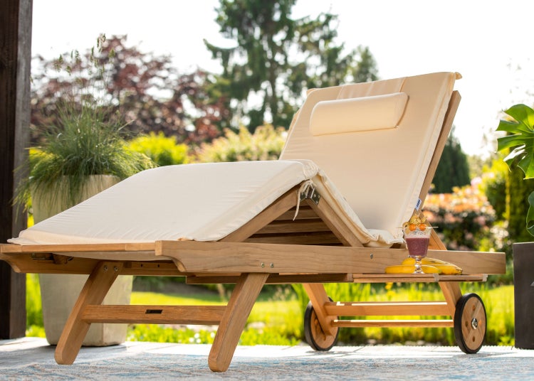 Holzliege mit Auflage und Getränk im Garten