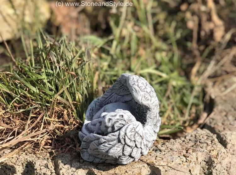 Kleine Engelsfigur aus Stein als Gartenfigur, schlafender Engel mit Flügeln als Grabschmuck oder Dekoration.