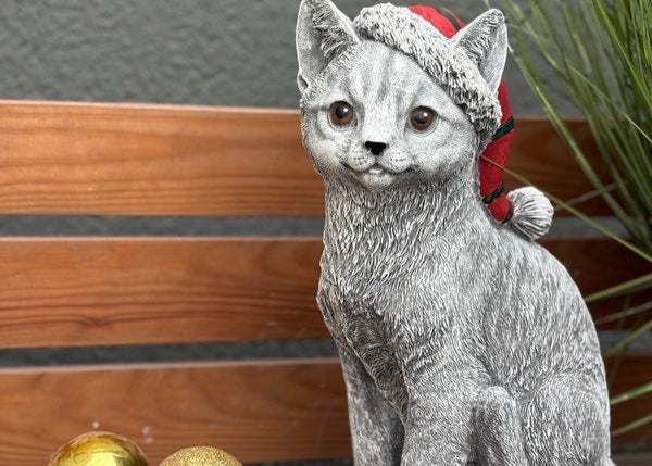 Steinfigur Katze mit Weihnachtsmütze als weihnachtliche Gartendekoration für den Außenbereich