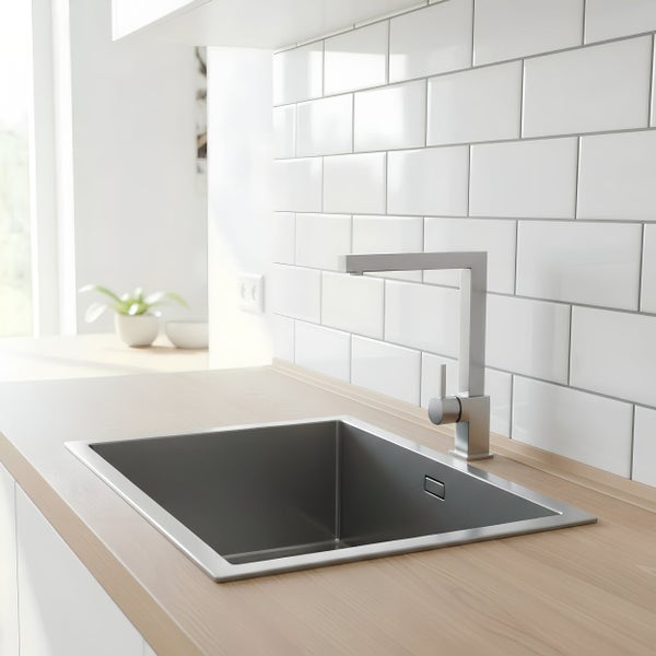 Moderne Küchenspüle aus Edelstahl mit passender Küchenarmatur in einer hellen, minimalistisch eingerichteten Küche mit Fliesenrückwand.