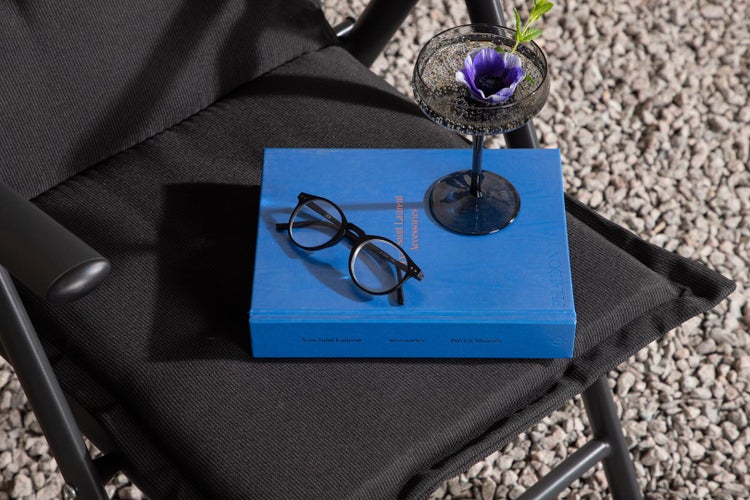 Szene auf einem Stuhl mit Buch, Brille und Cocktailglas