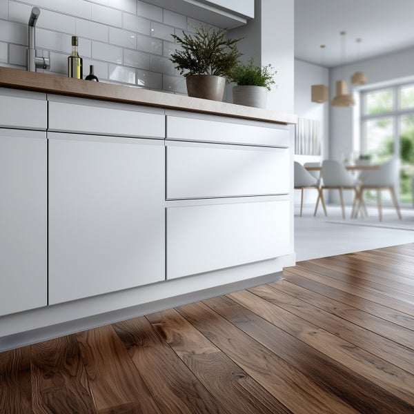 Detailansicht einer Küche mit weißen Schränken, Holzarbeitsplatte, Fliesenrückwand und Holzboden.