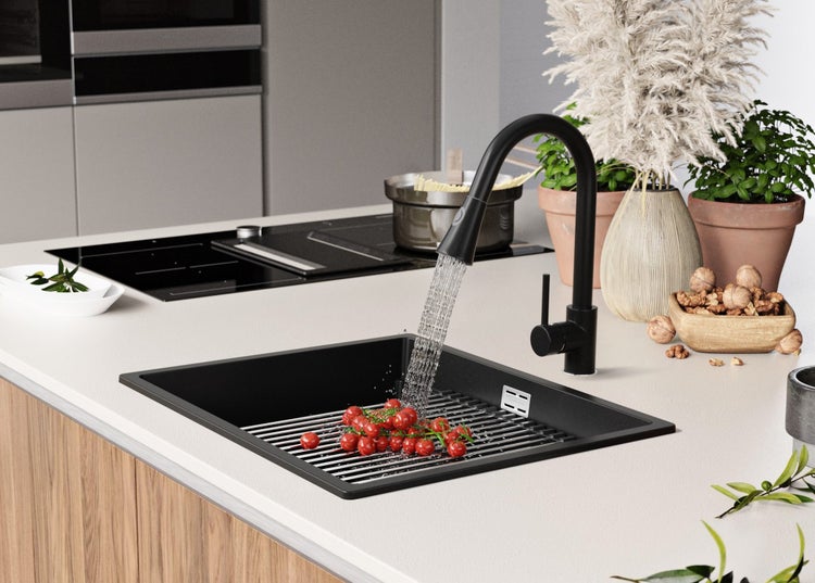 Spüle aus schwarzem Material mit Abtropfgitter und Wasserhahn in einer modernen Küche.