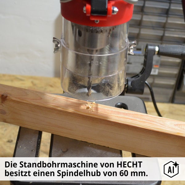 HECHT Standbohrmaschine beim Bohren eines Holzbretts mit transparentem Schutz und 60 Millimeter Spindelhub.