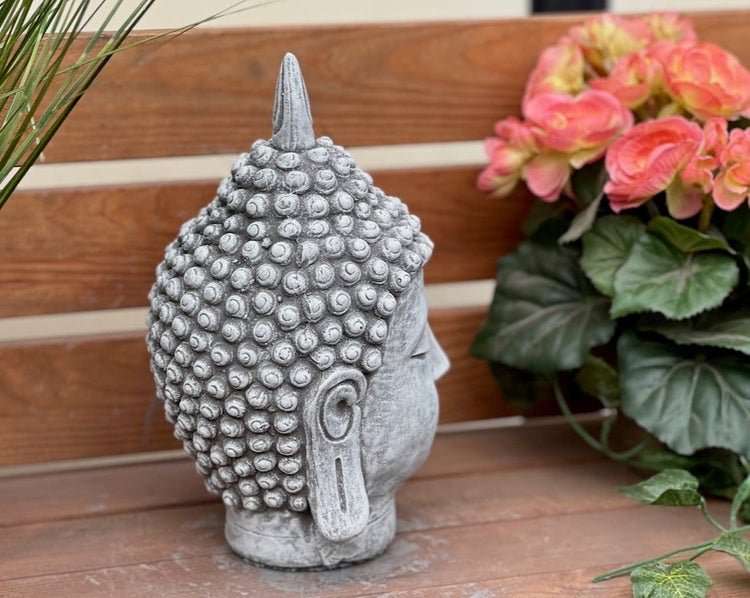 Buddha-Kopf Gartenfigur in Steinoptik auf einer Holzbank.