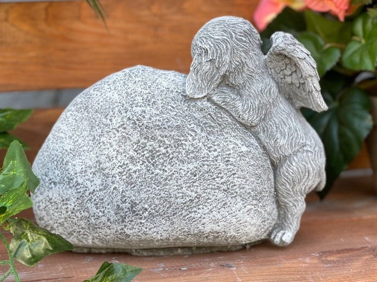 Steinfigur als Schutzengel Hund lehnend an einem Stein für den Garten