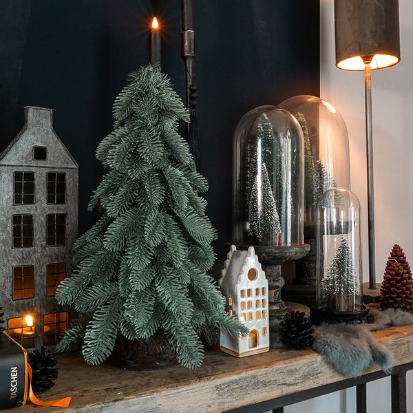 Dekoratives Stillleben mit künstlichem Weihnachtsbaum, Häusern und Glaskuppeln auf einem Tisch