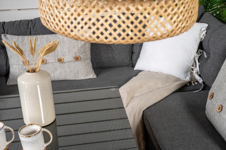 Terrasse mit Sofa, Kissen, Decke, Tisch und Dekoration unter einer Bambuslampe