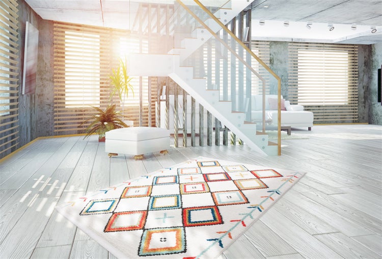 Moderner Teppich mit geometrischem Rautenmuster auf hellem Holzboden in einem lichtdurchfluteten Wohnzimmer mit Treppe und großen Fenstern.